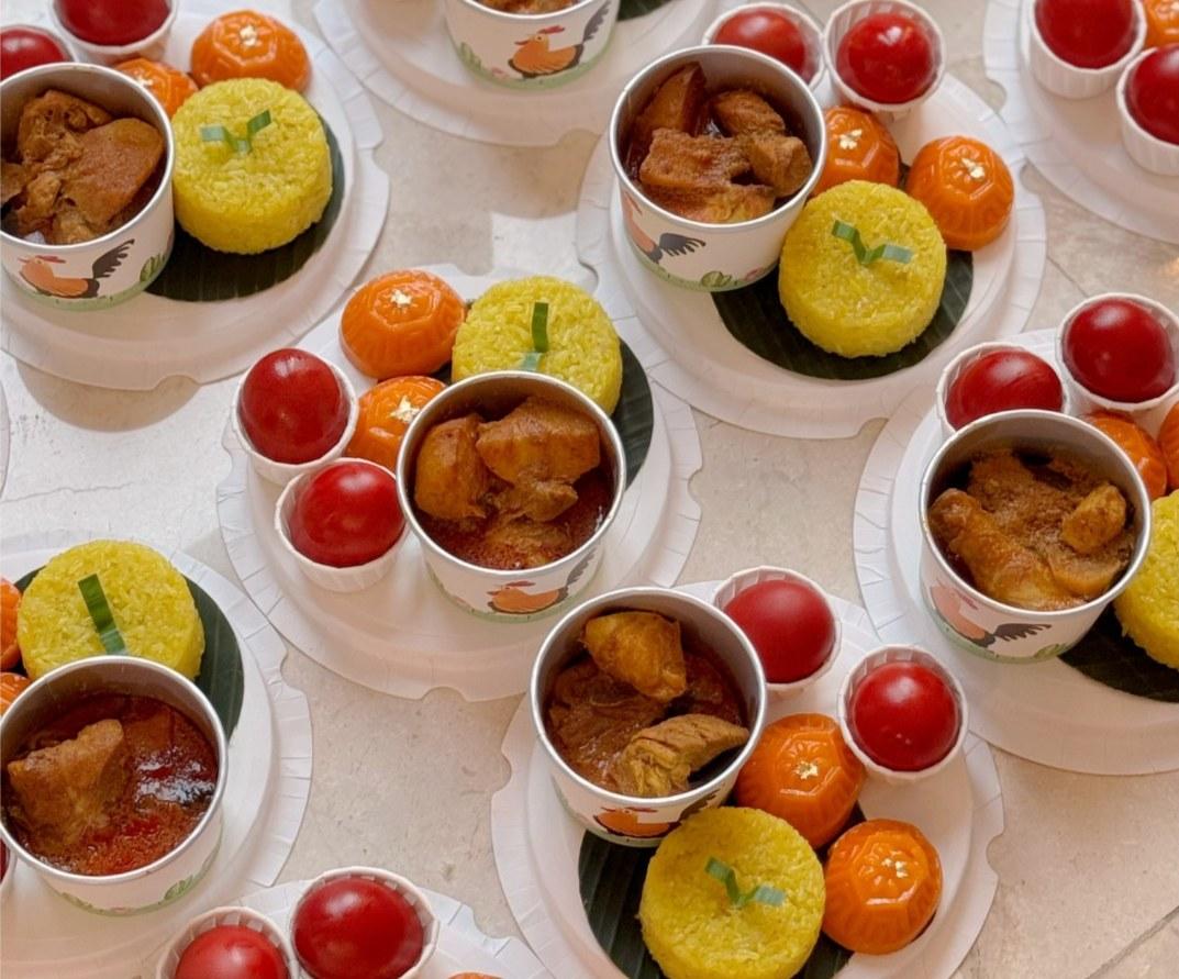 Traditional Gift Set with curry chicken and potato, nasi pulut kunyit, angku kuih and red eggs in round packaging.